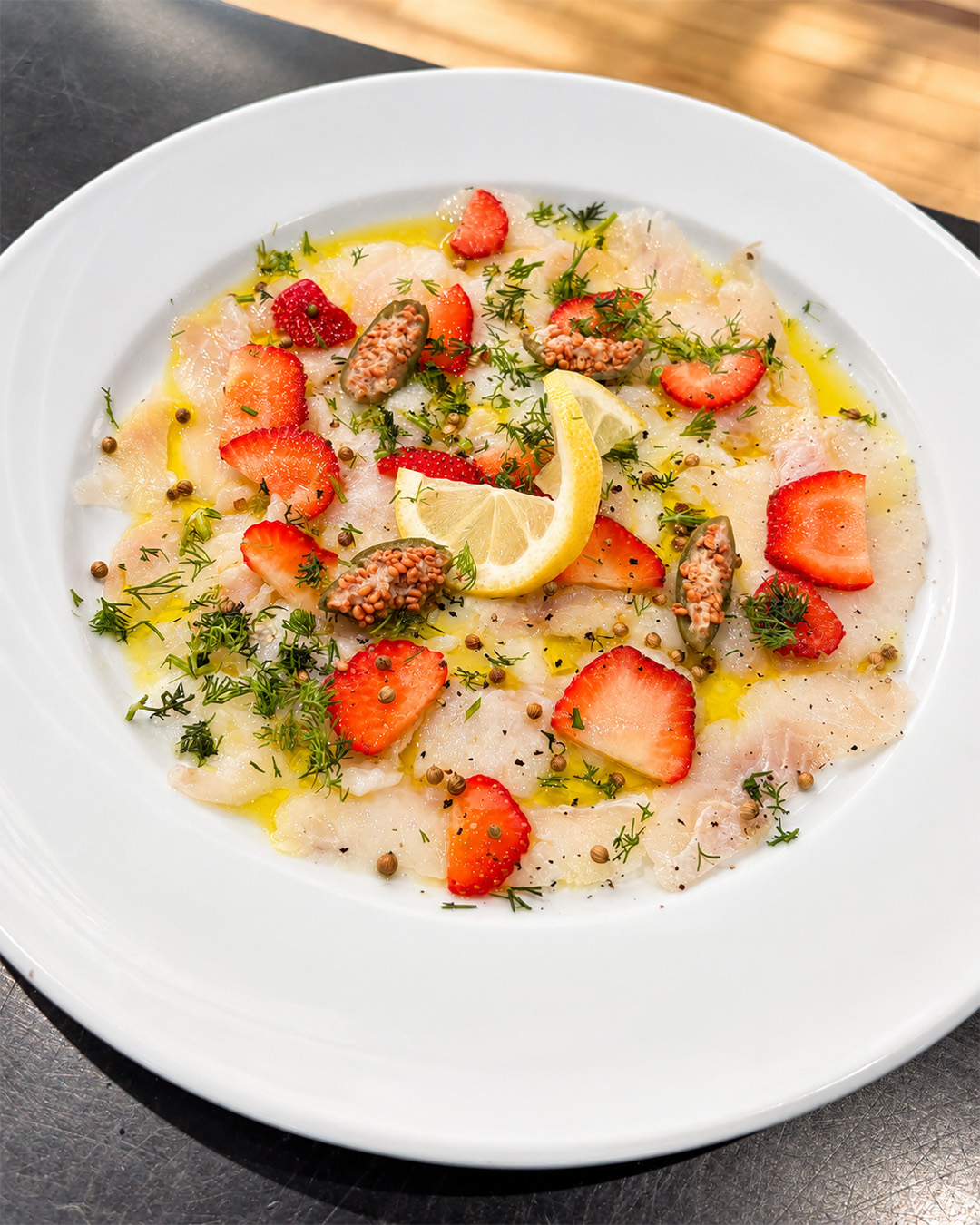 Fine assiette de poisson cru, fraises, citron, herbes et huile d'olive