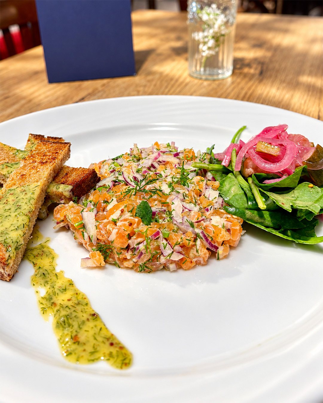Tartare de saumon aux herbes servi avec salade et pain toast&eacute;