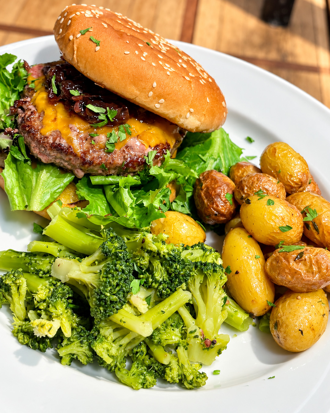 Burger servi avec pommes de terre r&ocirc;ties, brocolis et salade verte